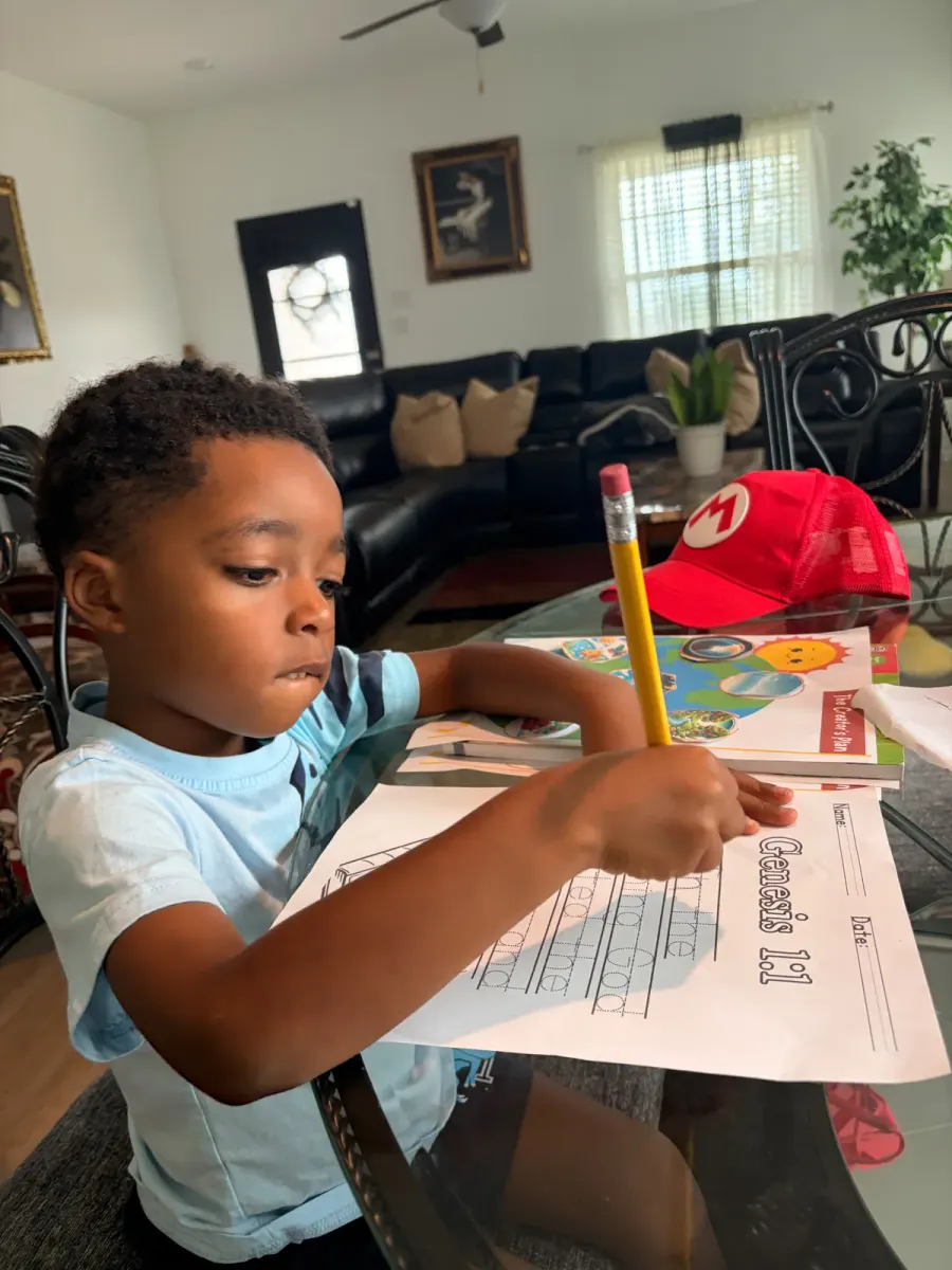 Preschool child writing Genesis 1:1 to build biblical literacy skills